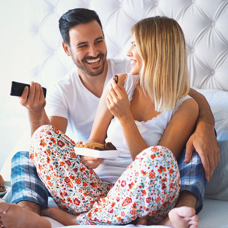 Happy couple on a bed with a tv remote